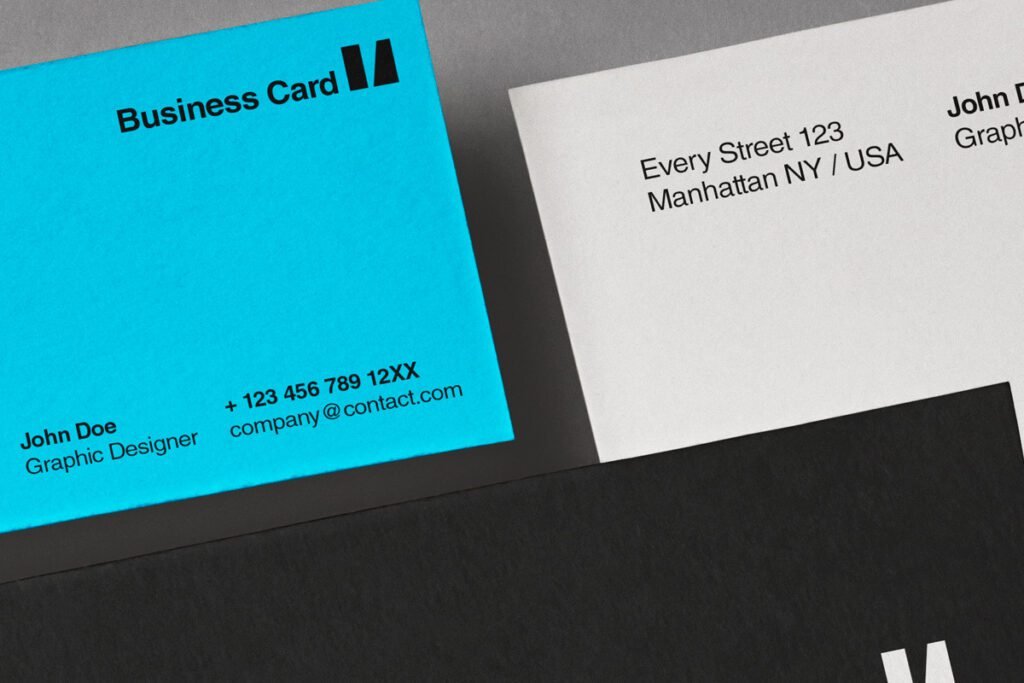 Close-up of corporate identity mockups featuring a bright blue business card, a white business card, and a black document, all with modern typography.