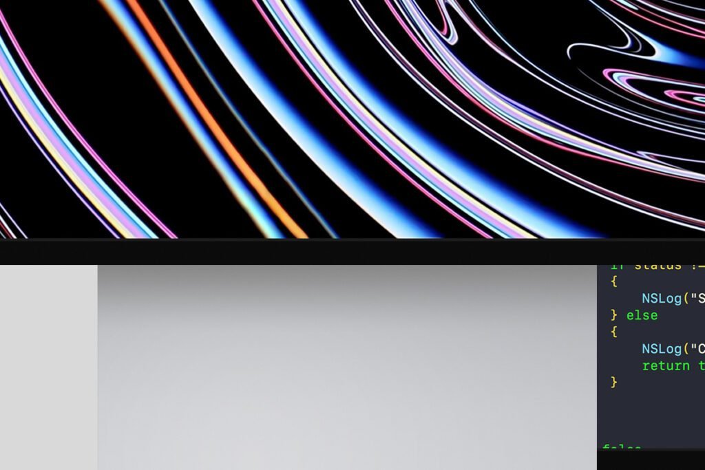 Top portion of an iMac screen mockup displaying an abstract colorful wallpaper, with a hint of a blank screen and code editor below.