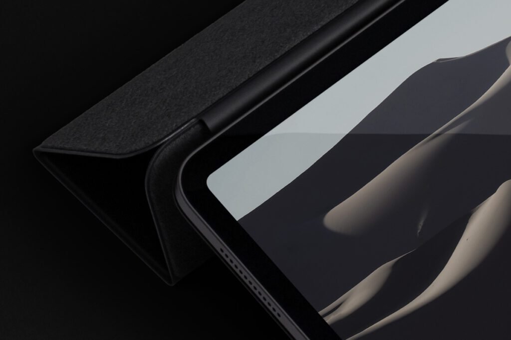 Close-up of an iPad Pro with a partially open dark gray smart cover, displaying a minimalist image on screen.
