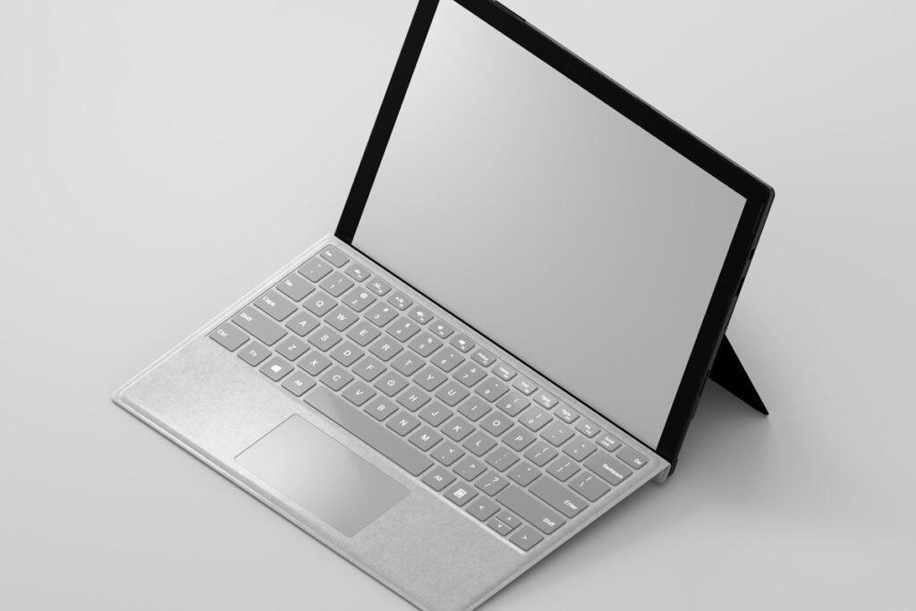 Isometric view of a minimalist silver laptop with a blank screen and a white keyboard, on a light grey background.