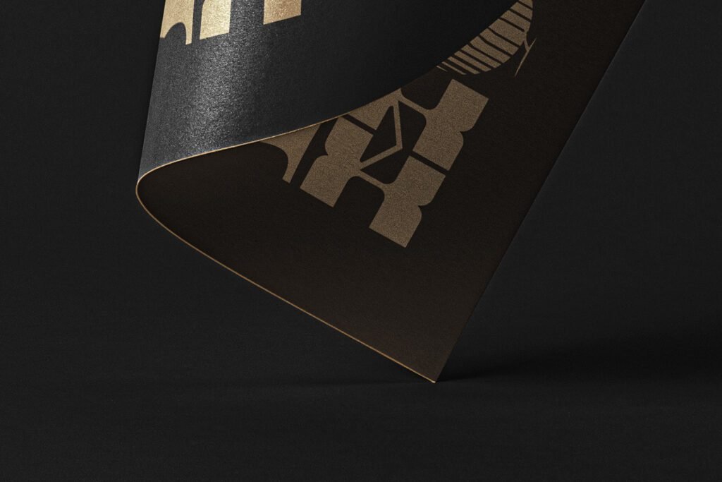 Luxury black paper mockup with golden foil stamped design, showcasing a curved edge and textured finish.