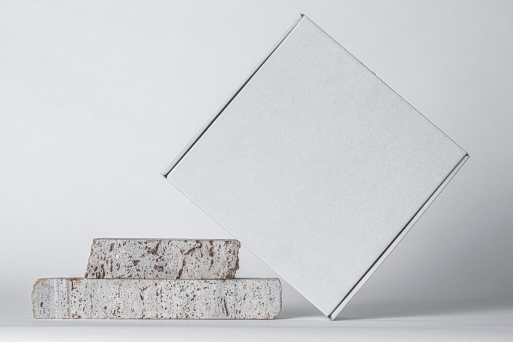 White mailer box leaning on rustic brick steps, minimalist packaging mockup