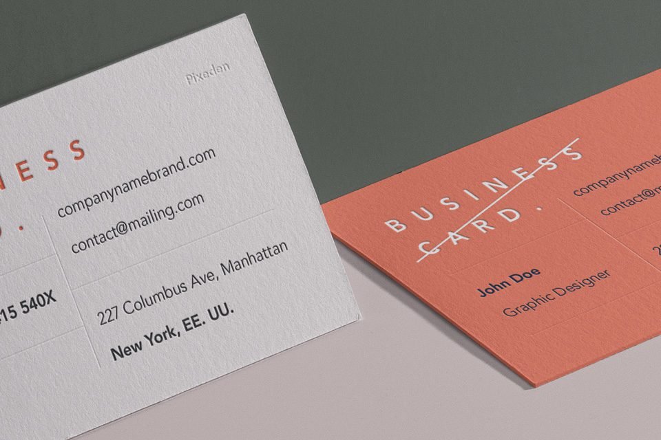 A close-up, angled view of two business cards; one off-white with black text and "BUSINESS" in orange, and another salmon pink with "BUSINESS CARD" in white. They are positioned as if on a wall.