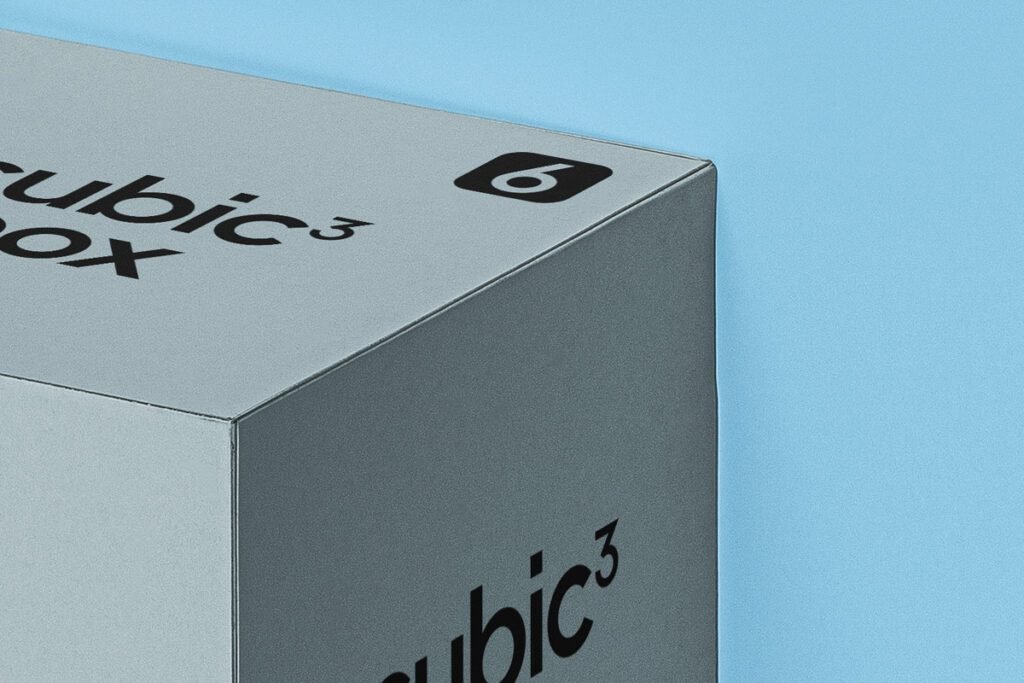A close-up, high-angle view of a light grey "Cubic Box" with "cubic³ box" branding on the top, a numbered logo on the corner, and "cubic³" on the side, set against a solid light blue background.
