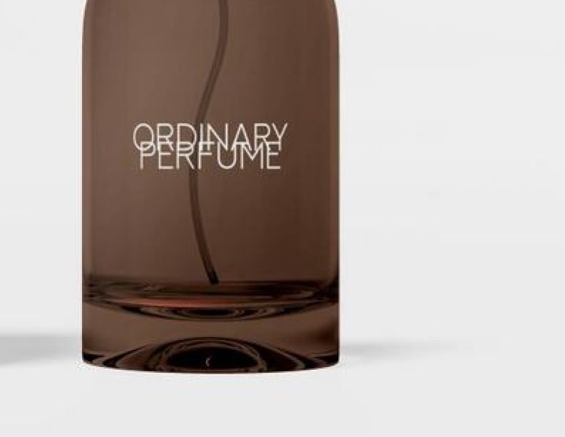A close-up of a dark amber perfume bottle mockup, showing the "ORDINARY PERFUME" brand name in white text and the internal spray tube, with empty space for text on the right.