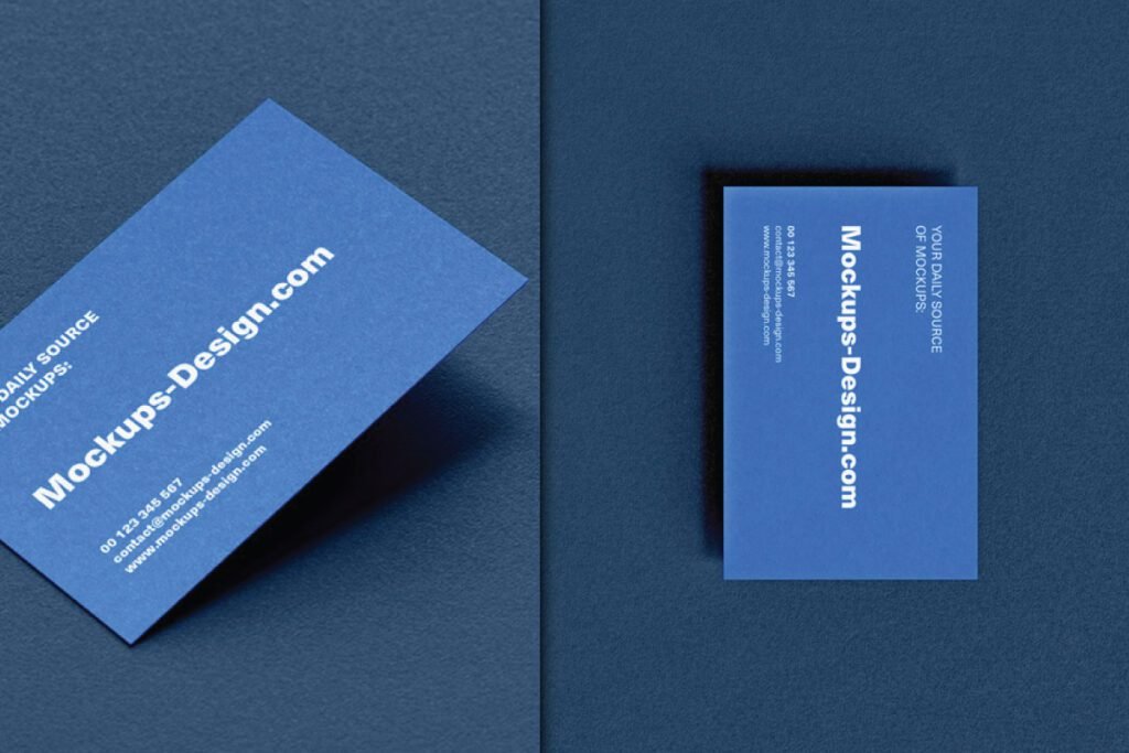 Two realistic horizontal business card mockup PSDs on textured paper, both blue with white text about Mockups-Design.com and contact information. One card is angled, and the other is straight.