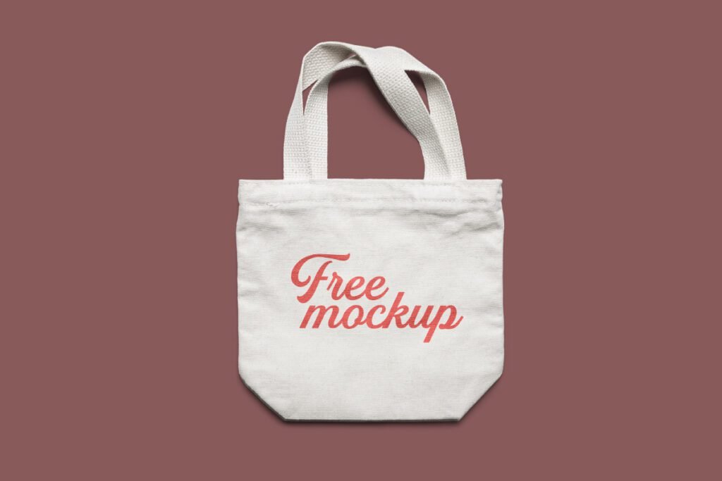 Small White Fabric Tote Bag Mockup PSD showing a white fabric tote bag with a red Free mockup text on a dark red background.