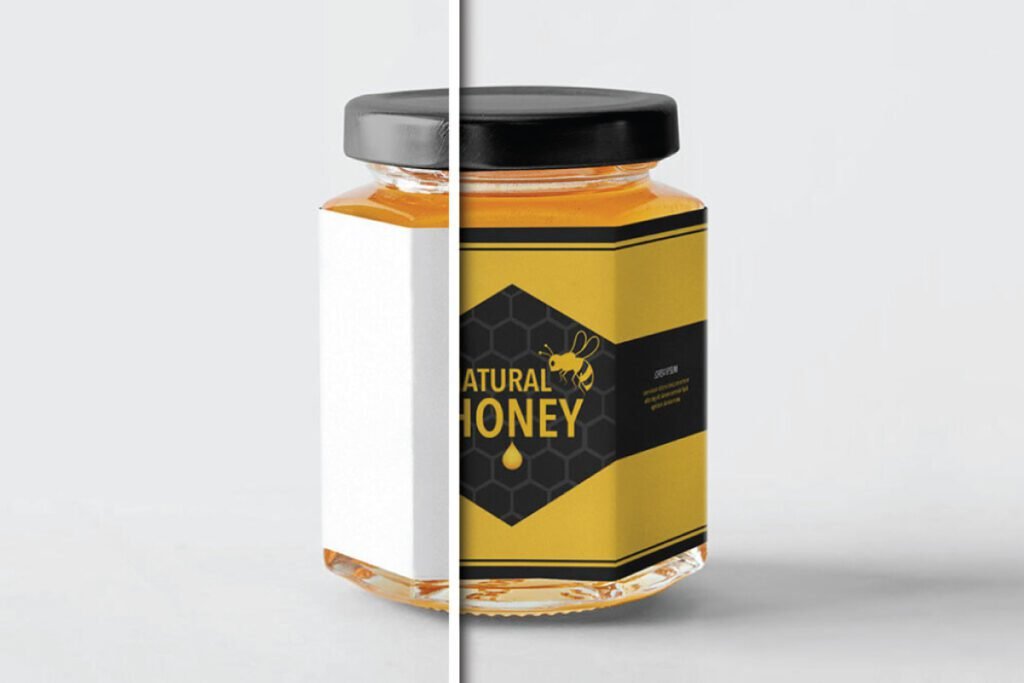 A side-by-side view of a hexagonal Honey Jar Mockup. The right half shows a jar with a black lid and a vibrant yellow and black label featuring a honeycomb pattern, a bee illustration, and "NATURAL HONEY" text. The left half of the image is plain white, obscuring part of the jar.