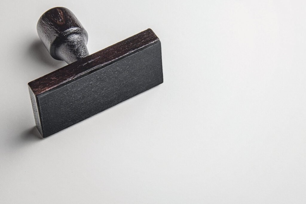 Rectangular Rubber Stamp MockUp PSD showing a blank black rubber stamp with a dark wooden handle laying on a white surface, leaving ample copy space.
