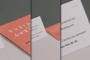 A close-up, angled view of two business cards in a wall perspective mockup. One card is salmon pink with "BUSINESS CARD" embossed, and the other is off-white with contact details.
