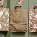 Best Zero Waste Eco Paper Bag Mockup PSD displays three hands holding brown paper bags. One bag has a white leaf pattern with recycle symbols. The middle bag is plain. The third bag has a light pink ornate pattern.