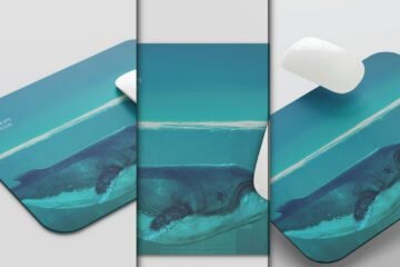 A white computer mouse rests on a rounded rectangular mouse pad mockup PSD featuring an underwater whale design, with two additional mouse pads shown in the background.