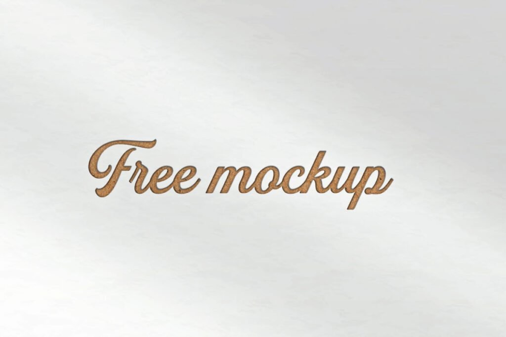 A paper with debossed effect logo mockup shows the words Free mockup in a cursive script font. The logo has a brown, pressed-in texture on a light, textured paper background.